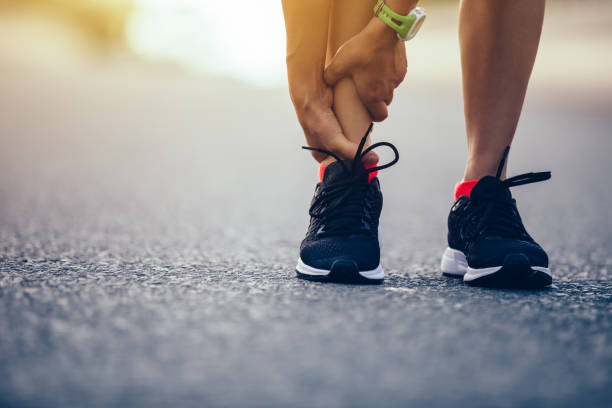 woman runner hold her injured leg on road - asian ethnicity jogging female women imagens e fotografias de stock