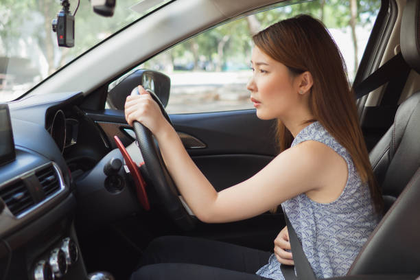 Asian woman having painful stomachache in car while drive ,Female suffering from abdominal pain,Period cramps stock photo