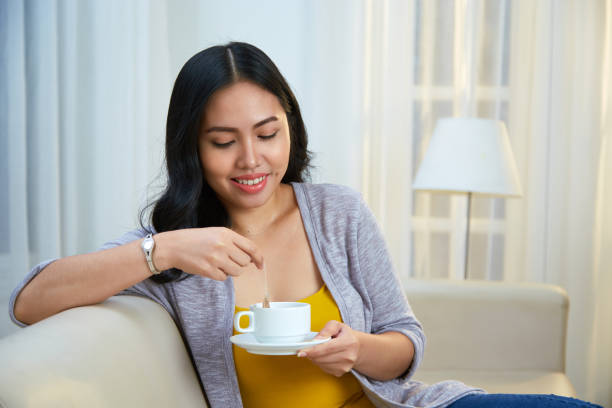 Pretty woman drinking tea Smiling lovely young Asian woman putting tea bag in cup hot filipina women stock pictures, royalty-free photos & images