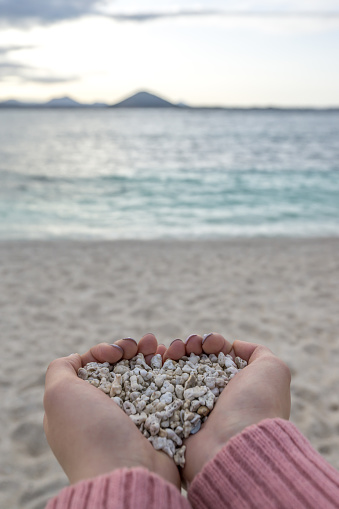 Hands holding on to white pebbles in Udo Sanho Beach or Seobinbaeksa in Jeju Island, South Korea