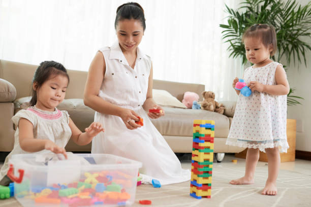 Mother playing with daughters Smiling pretty Vietnamese woman playing with little daughters at home asian toddler fewer toys stock pictures, royalty-free photos & images