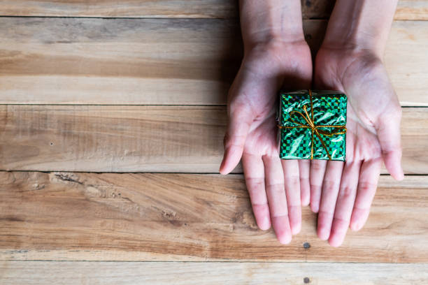 istock Female hand holding gift box on wooden table 1084780416