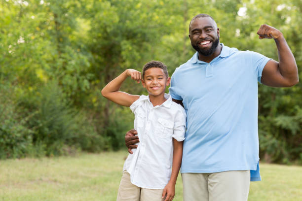 le père et son fils courbant leurs biceps. - child human muscle flexing muscles little boys photos et images de collection