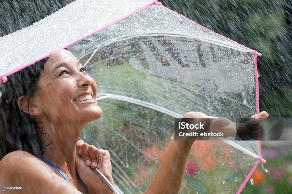 Giovane donna con un ombrello a pioggia - Foto stock royalty-free di Pioggia