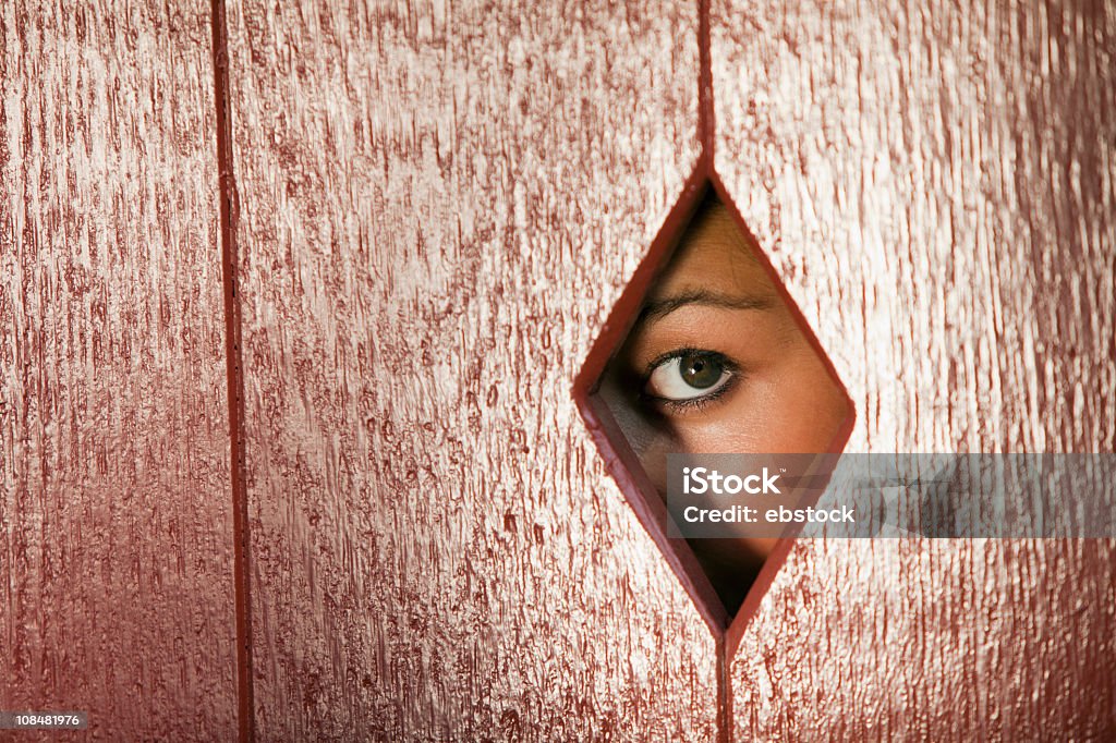 Mujer mirando a través de un orificio en la pared - Foto de stock de Adulto libre de derechos