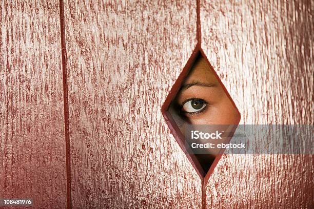 Mujer Mirando A Través De Un Orificio En La Pared Foto de stock y más banco de imágenes de Adulto - Adulto, Agujero, Cara oculta