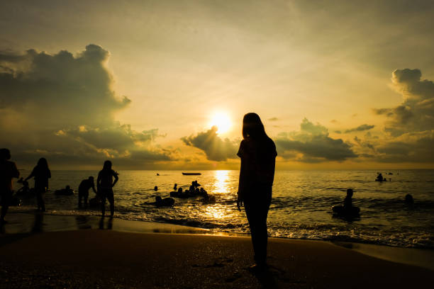 istock Female silhouette standing on the beach watching the sunset 1084826296