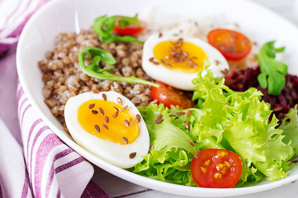 istock Buckwheat porridge buddha bowls with beetroot, cabbage, boiled eggs and  fresh tomato on white table. Healthy breakfast. 1084828366