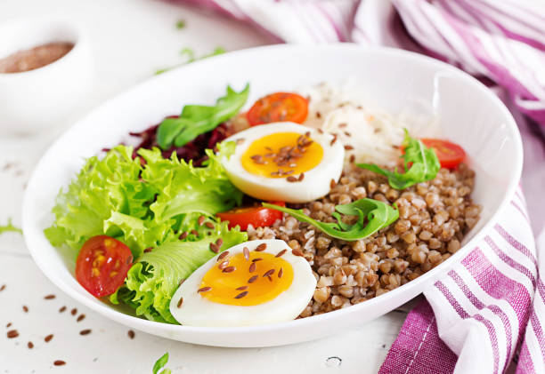 istock Buckwheat porridge buddha bowls with beetroot, cabbage, boiled eggs and  fresh tomato on white table. Healthy breakfast. 1084828370