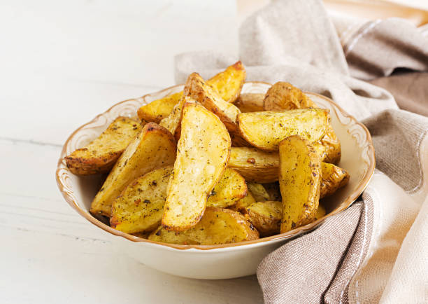 istock Ruddy Baked potato wedges with garlic on a white background. 1084828894