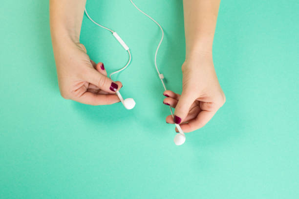 istock two female hands holding white headphones on menthol background 1084836356