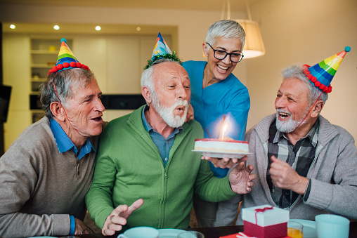 Senior friends looking at the man blowing his birthday candle