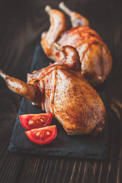 istock Two baked quails wrapped in bacon on the black stone board 1084840242