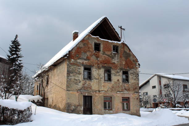 istock Abandoned ruined house with broken windows and fallen bricks covered in snow 1084848830