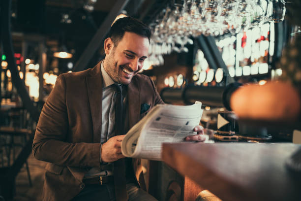 Young businessman reading newspaper at the bar