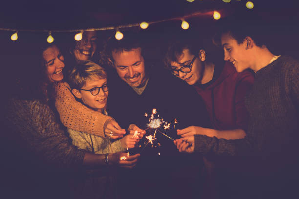 Night party celebration like new year eve 2019 or Christmas for caucasian big modern family using sparkles light fireworks together in friendship having fun - people smiling and do party with different ages and generations celebración de la fiesta de noche como 2019 de la víspera de año nuevo o navidad para la familia moderna grande caucásica con destellos encender los fuegos artificiales juntos en amistad diversión - gente sonriendo y fiesta con diferentes edades y gen
