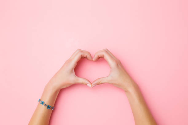 ハート パステル ピンク背景に若い女性の手から作成されました。愛と幸福の概念。感情的、感傷的なテキスト、引用または格言の空の場所。クローズ アップ。平面図です。 - love hope valentines day horizontal ストックフォトと画像