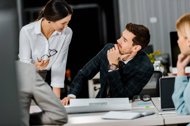 istock partial view of businesspeople having conversation at workplace with papers in office 1084853730