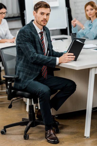 istock young businessman with notebook sitting at workplace in office 1084853744