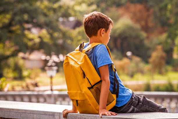 triste rapaz sozinho sentado no parque ao ar livre - back school - fotografias e filmes do acervo