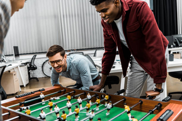 istock smiling multicultural businessmen playing table football in office 1084862772