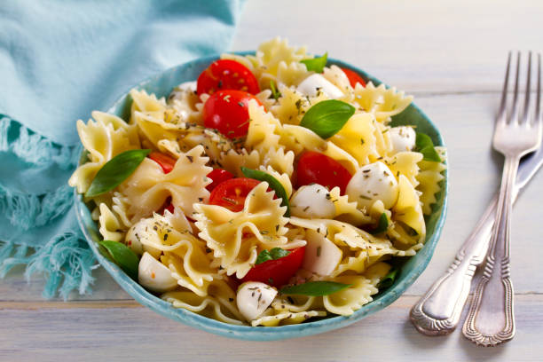 istock Caprese Pasta Salad. Pasta with mozzarella cheese, tomatoes and basil 1084863148