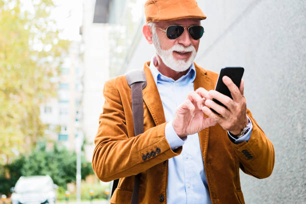 istock Fashionable Senior Man Outdoors with sunglasses reading massage 1084865282