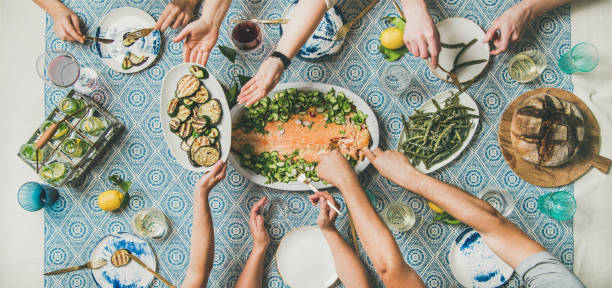 istock Friends sharing mediterranean style dinner with cooked salmon, bread, lemonade 1084870814