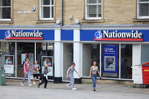 People walk by Nationwide Building Society branch in Huddersfield, UK. NBS is the largest building society in the world. It had 495.3 million GBP annual income in 2009.
