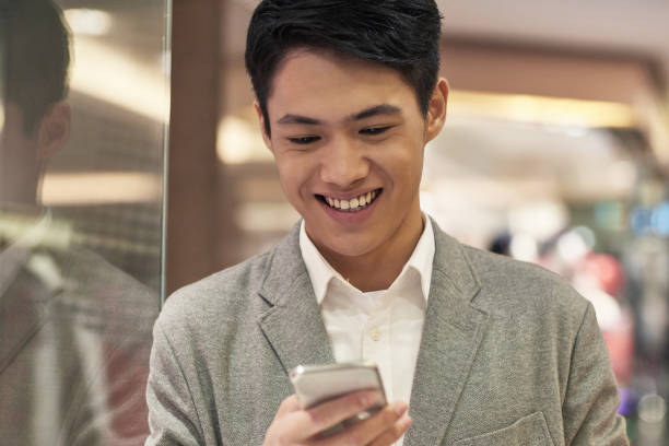 istock Smiling man using mobile phone in shopping mall 1084890454