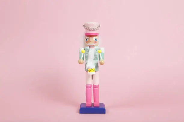 wood nutcracker figurine placed on a pink background. Color harmony. Minimal still life color photography