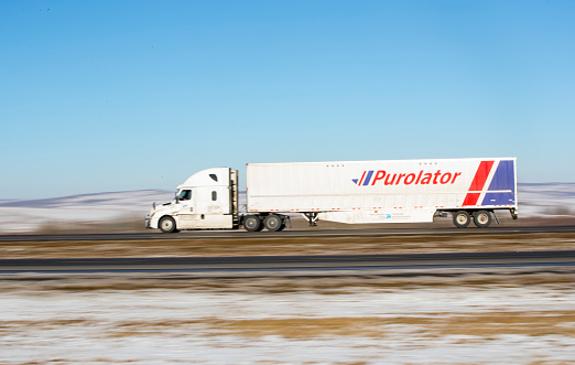A Purolator truck hauling cargo west on the trans-canada highway near Canmore, Alberta. Taken on November 24, 2018