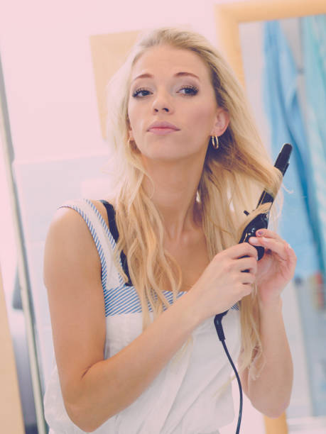 istock Woman using hair straightener 1084896870