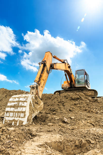 escavatore al lavoro in cantiere nella giornata di sole - earth mover working field dirt foto e immagini stock