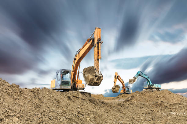 koparka pracująca na budowie w pochmurny dzień - earth mover working field dirt zdjęcia i obrazy z banku zdjęć