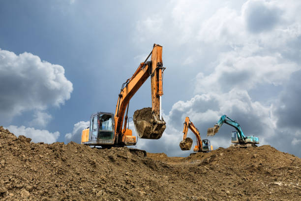 koparka pracująca na budowie w pochmurny dzień - earth mover working field dirt zdjęcia i obrazy z banku zdjęć