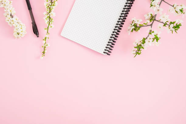 istock Frame with spring flowers and notebook with pen on pink background. Flat lay, top view. 1084902878