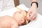 Infant medical exam - doctor checking head size with a measurement tape