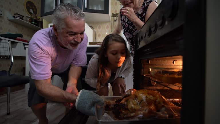 Grandparents and Granddaughter Checking the Traditional Turkey for Christmas Dinner