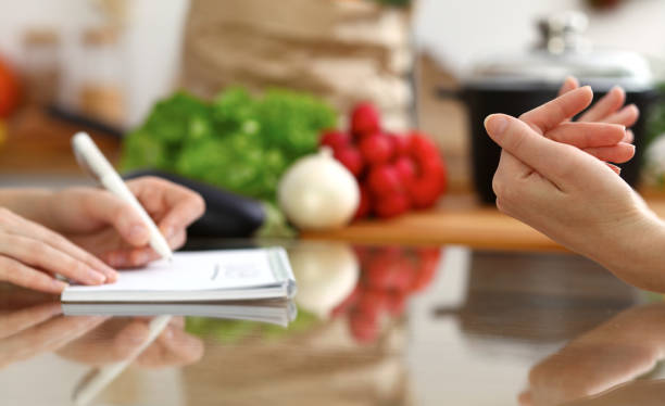 istock Closeup of human hands discussing something while cooking in kitchen. Women talking about menu. Family dinner, friendship and lifestyle concept 1084922760