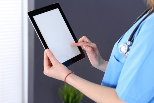 istock Woman doctor using tablet computer while standing straight in hospital office, closeup. Healthcare, insurance and medicine concept 1084931300