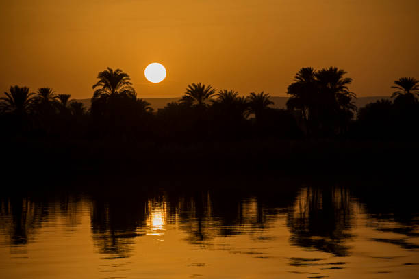 View across large wide river Nile in Egypt through rural countryside landscape with beautiful orange sunset