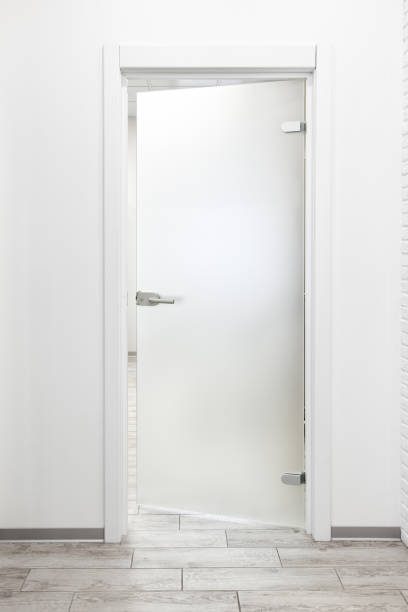 Minimalist white office interior with frosted glass door ajar Minimalist modern office interior with white wall and frosted glass door ajar ajar stock pictures, royalty-free photos & images