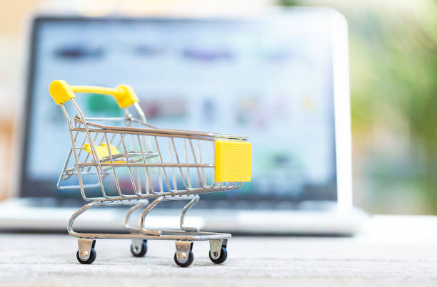 istock Shopping cart with laptop computer on a bright background 1084949446
