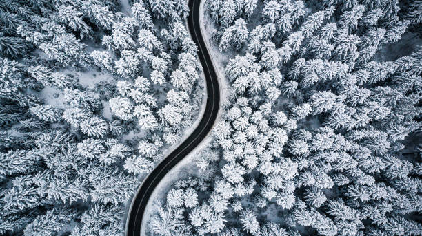 istock Curvy windy road in snow covered forest, top down aerial view 1084950014