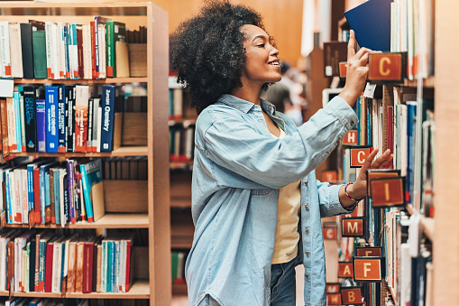 Young African-American ethnicity woman searching books in a library