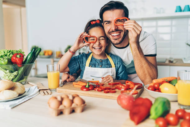 Father and daughter looking through pepper slices Playful grandmother and granddaughter in the kitchen happy fathers day funny stock pictures, royalty-free photos & images