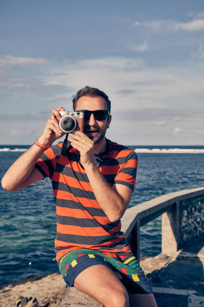 istock Man using vintage film camera on a ocean / sea vacation. 1084962052