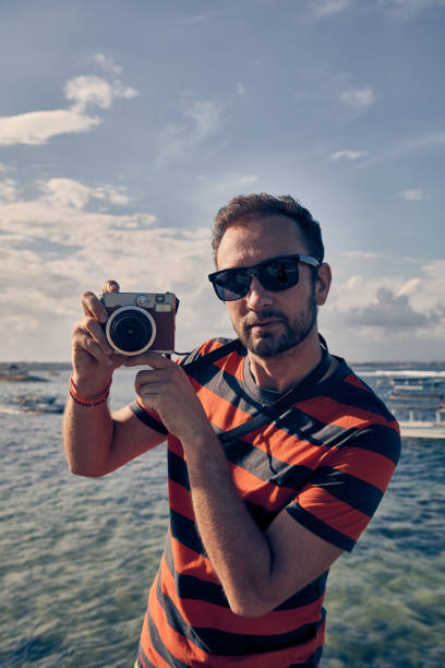 istock Man using vintage film camera on a ocean / sea vacation. 1084964608