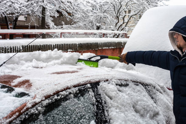 istock Young man cleaning his car from snow with brush 1084967578